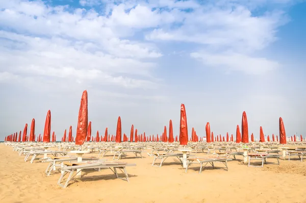 红色遮阳伞和日光浴浴床在里米尼海滩-本赛季初的意大利夏季概述 — 图库照片