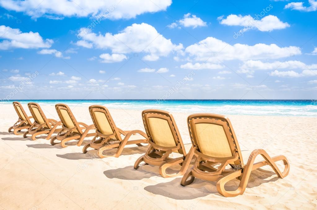 Sunbeds chaise longue at tropical empty beach and turquoise sea - Panorama of dream vacation in exclusive destination with white sand in a sunny beautiful day