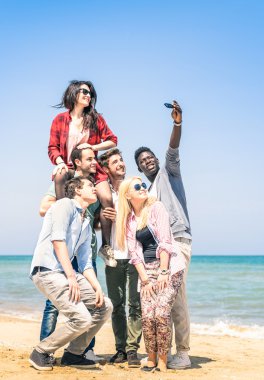 Group of multiracial happy friends taking a selfie at the beach - Concept of international friendship all together against racism