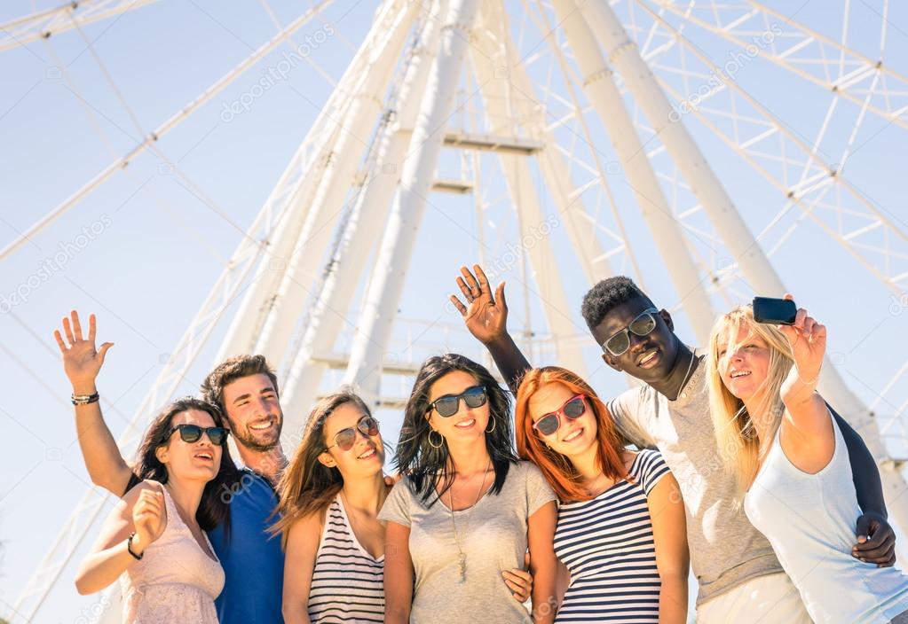 Group of multiracial happy friends taking a selfie at ferris wheel - International concept of happiness and multi ethnic friendship all together against racism for peace and fun