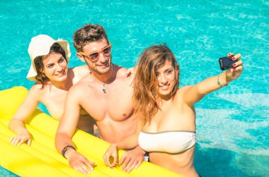 Group of best friends taking selfie at the swimming pool with yellow airbed - Concept of friendship in the summer with new trends and technology - Young man with girlfriends enjoying modern smartphone clipart