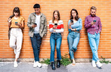 Üniversitenin arka bahçesinde akıllı telefon kullanan çok kültürlü insanlar grubu cep telefonu bağımlısı Milenyal arkadaşlar her zaman bağlı öğrencilere sahip teknoloji konsepti