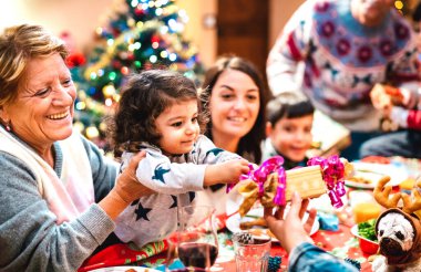 Geniş bir çoklu kuşak aile Noel yemeğinde eğleniyor - Kış tatili - Ebeveynler ve çocuklarla birlikte akşam yemeğinde hediyeleri açmak kavramı - Küçük kızına odaklan - Sıcak filtre