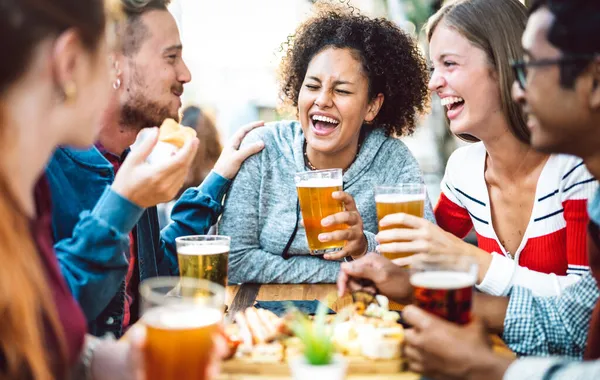 醸造所のパブの庭でビールを飲む多人種の友人 オープンエアのバーのドアで一緒に幸せな時間の食べ物を楽しんでいる男と女の子との真の友情のライフスタイルの概念 暖かい鮮やかなフィルター — ストック写真