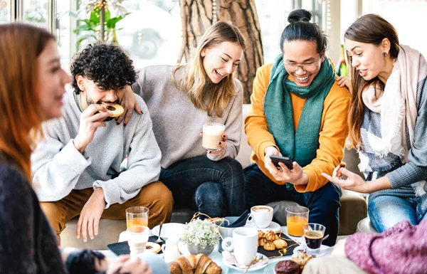 コーヒーバーで携帯電話で遊ぶ多文化の友人 ブランチタイムでカフェテリアで一緒に楽しむ人々 カフェ会場で幸せな男性と女性とのライフスタイルの概念 明るい暖かいフィルター — ストック写真