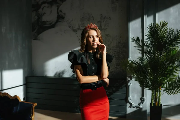 スカートに赤い石の冠を持つ壁の隣のスタジオには美しい女の子が立っています。 — ストック写真