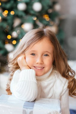 Close-up portrait of a little girl with big eyes and a wide sincere cute smile during the New Year holidays, the concept of Christmas . High quality photo