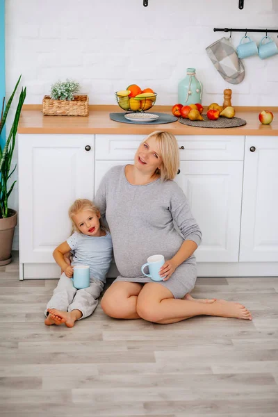 Pregnant Girl Sits Little Blonde Floor Kitchen Blue Cups Her — Stock Photo, Image