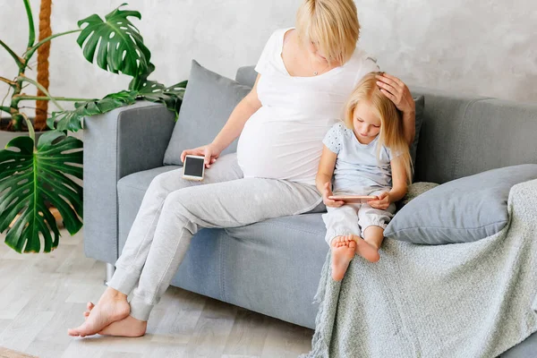 Pregnant Young Girl Sitting Sofa Her Little Daughter Playing Phones — Stock Photo, Image