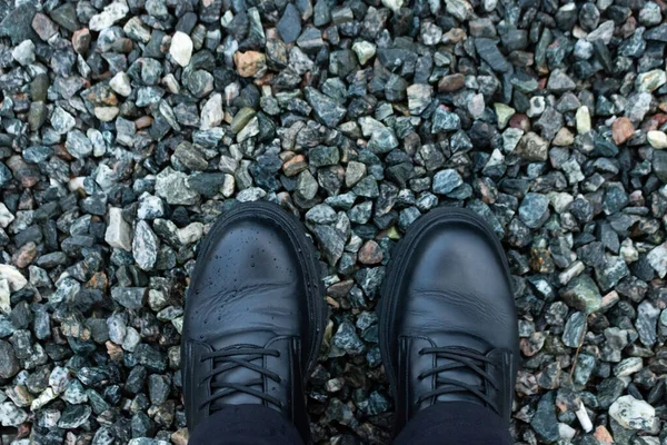 Ayakları siyah çizmeli, küçük siyah kayalıklarda. Yakın plan. Üst görünüm