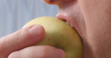 A person bites off an apple close-up.