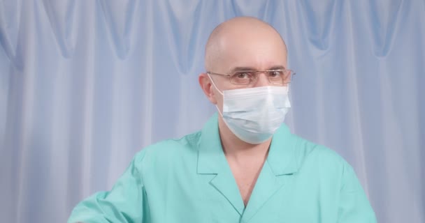A doctor in a medical mask and rubber gloves shows a large enema. — стоковое видео