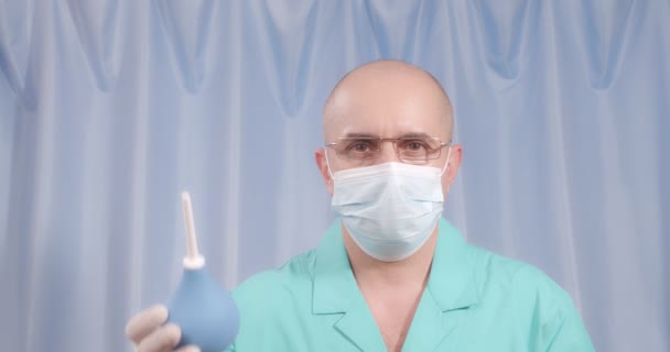 The doctor holds an enema in his hands. Blue pear syringe. — Vídeo de Stock