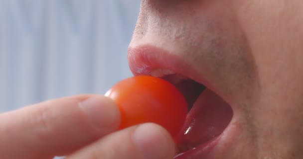 A man eats a cherry tomato close-up. — Wideo stockowe