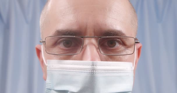 A masked doctor wears glasses. Glasses fog up from breathing. Close-up. — Stockvideo