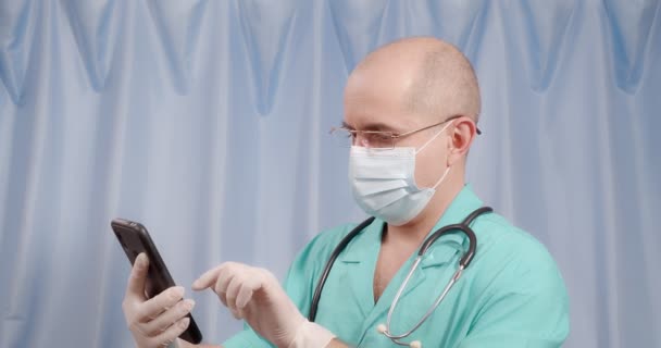 Le médecin cherche des informations sur le téléphone portable sur un fond bleu. — Video