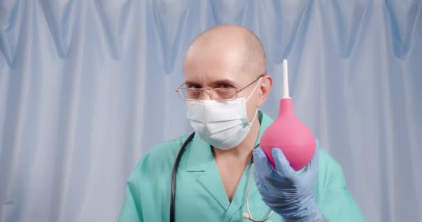 Le docteur tient un lavement dans ses mains. Seringue de poire rose. — Video