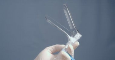 Lastik eldivenli bir el jinekolojik bir alet tutar..