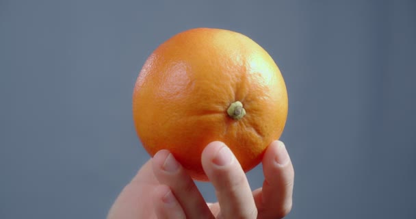 Ręka pokazuje pomarańczę na niebieskim tle.. — Wideo stockowe