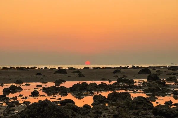 Silhouette roter Himmel über einer felsigen Meeresküste. Sonnenuntergangslandschaft — Stockfoto