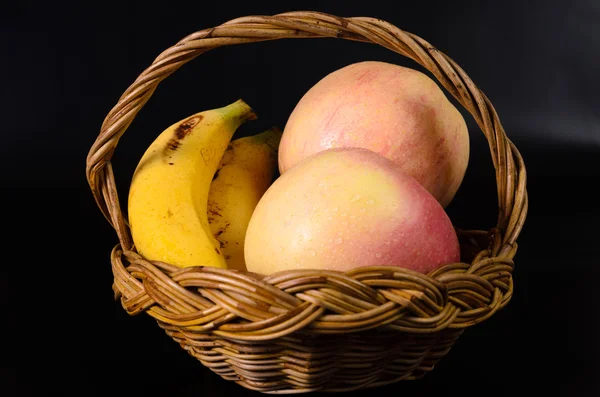 リンゴと黒の背景にバスケットのバナナ — ストック写真