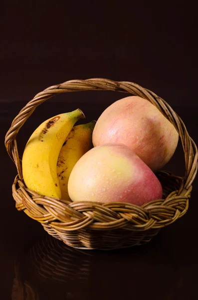 リンゴと黒の背景にバスケットのバナナ — ストック写真