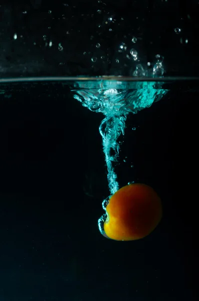 Plusk wody w pomidora na czarnym tle — Zdjęcie stockowe