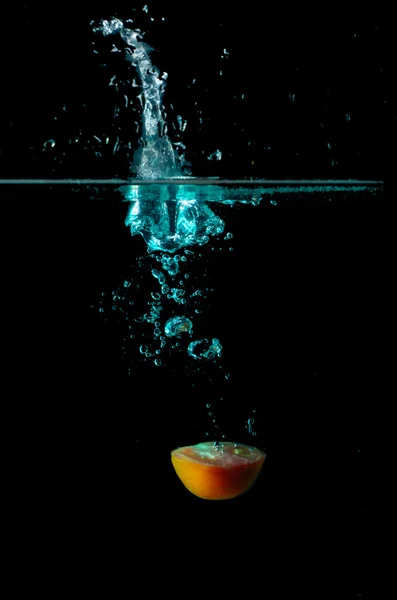 Tomaat water splash op zwarte achtergrond — Stockfoto