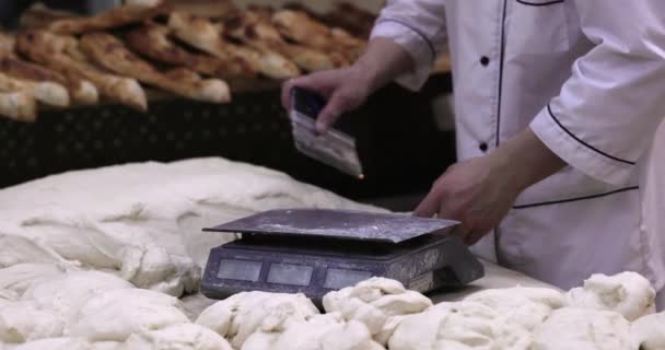 面包师在生产设施中为烘烤面包切面团并称其重量 一个人在面包店里把生面团按比例称重 — 图库视频影像