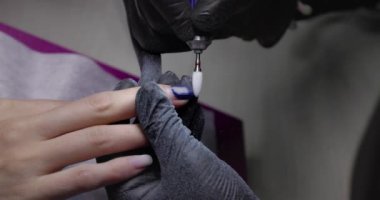 Nail master remove nail polish in beauty saloon with electric file nail. Manicure master in  black gloves removes gel polish from nails using a cutter. Hardware manicure close-up. Shellac nail coating