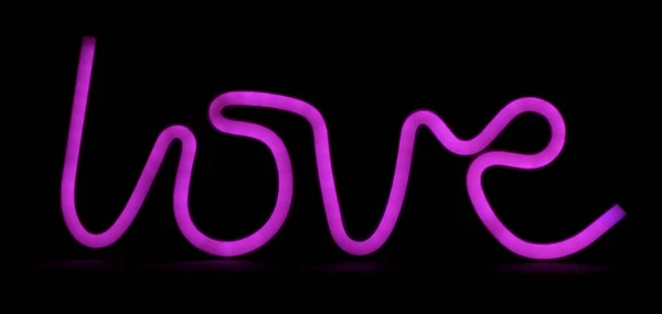 Beautiful neon inscription love in purple on a black background. Photo of a glowing inscription love.