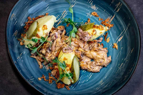 Beef stroganoff, goulash, with sauce and mushrooms, boiled potatoes.National Russian dish of beef stroganoff with meat, boiled potatoes, mushrooms and fried onions.