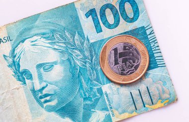 Brazilian Real banknotes and a 1 Real coin in macro photography. Brazilian economy and finance.