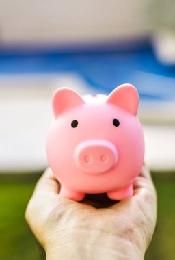 pink piggy bank with a hand blurred background 