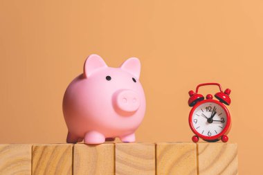 composition of wooden cubes, piggy bank and red alarm clock, business finance concept  