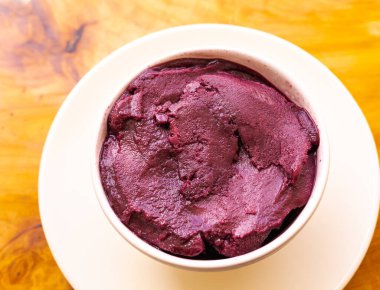 frozen acai served in white bowl in closeup photo on wooden background. Brazilian food.
