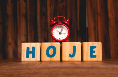 The word hoje (now) written in the Portuguese language on wooden blocks with a red clock in the image composition.