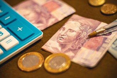 Real - BRL, money from Brazil. Folded money notes of the Brazilian Real in macro photography on a office table with calculator and coins 