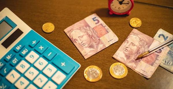 Real - BRL, money from Brazil. Folded money notes of the Brazilian Real in macro photography on a office table with calculator and coins