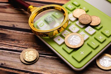 Brazilian currency. A magnifying glass over coins on calculator in the image composition. Photo about the Brazilian economy and the moment of crisis with high inflation.