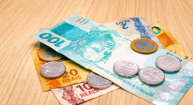 Brazilian Real banknotes and coins on a wooden table. Close-up photography. Brazilian economy and finance.
