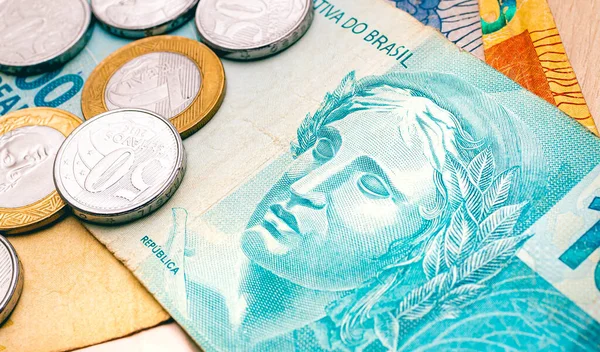 Brazilian Real banknotes and coins on a wooden table. Close-up photography. Brazilian economy and finance.
