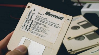 Hand holding white installation diskette with Windows 95