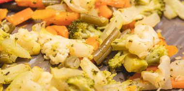 Vegetables sauted inside a frying pan in closeup photo. Broccoli, carrots, green beans and cauliflower.