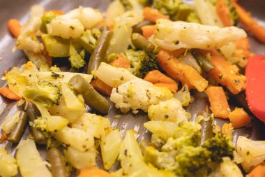 Vegetables sauted inside a frying pan in closeup photo. Broccoli, carrots, green beans and cauliflower.