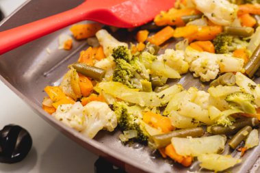 Vegetables sauted inside a frying pan in closeup photo. Broccoli, carrots, green beans and cauliflower.