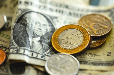 Real (BRL), money from brazil. real coins on US dollar bills. Photo representing the exchange idea.