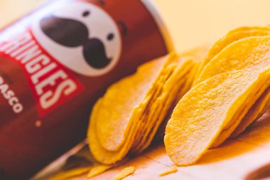 Brasilia, Federal District - Brazil. August, 30, 2022. barbecue-flavored pringles potato chips spread on a wooden board.