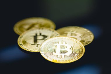 Bitcoin, BTC, kripto para birimi. Karanlık bir masanın yüzeyinde altın sikkeler ve yakın çekim fotoğraflarında cam..