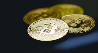 Bitcoin, BTC, kripto para birimi. Karanlık bir masanın yüzeyinde altın sikkeler ve yakın çekim fotoğraflarında cam..